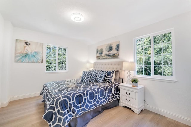 bedroom with multiple windows and light hardwood / wood-style flooring