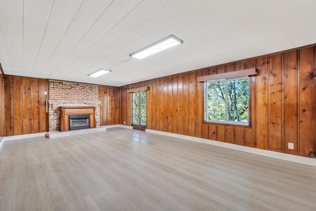 unfurnished living room with a healthy amount of sunlight, a fireplace, and light wood-type flooring