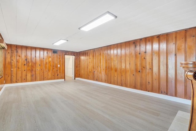 basement featuring wooden walls and light wood-type flooring