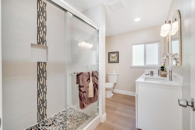 bathroom with walk in shower, wood-type flooring, vanity, and toilet