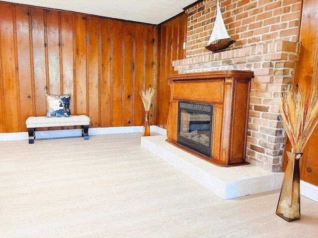 living area with light hardwood / wood-style floors, a large fireplace, and wood walls