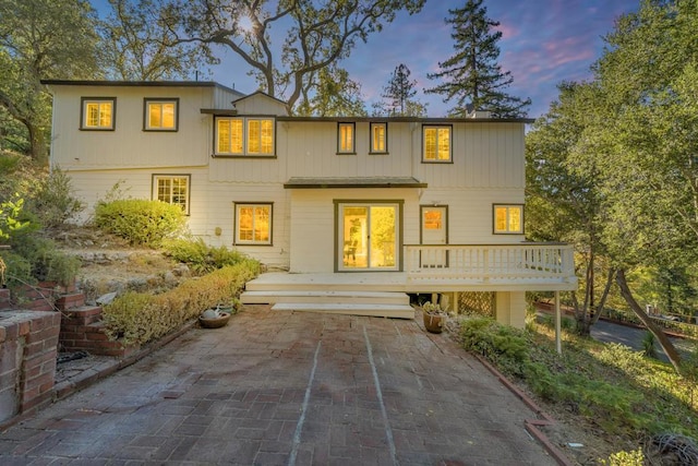 back house at dusk featuring a wooden deck