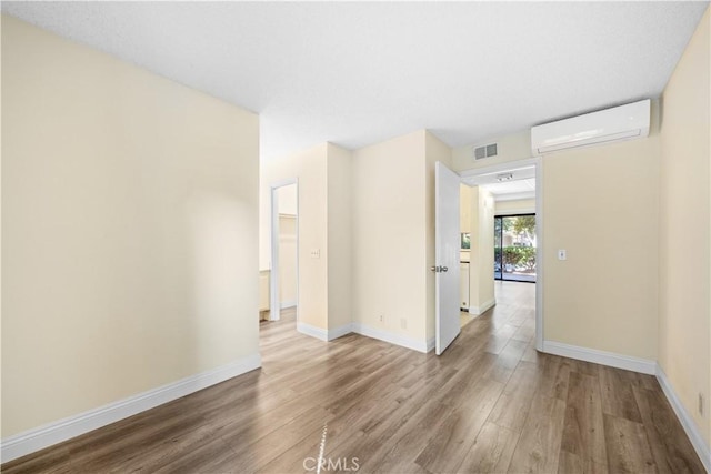 empty room with an AC wall unit and hardwood / wood-style flooring