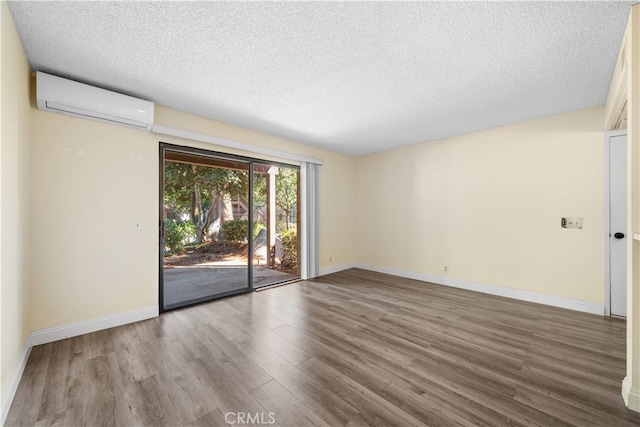 spare room featuring hardwood / wood-style floors, a textured ceiling, and a wall mounted AC