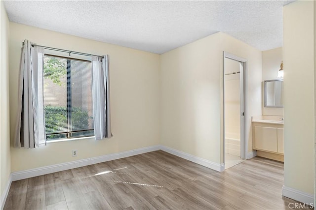 unfurnished room with light hardwood / wood-style floors and a textured ceiling