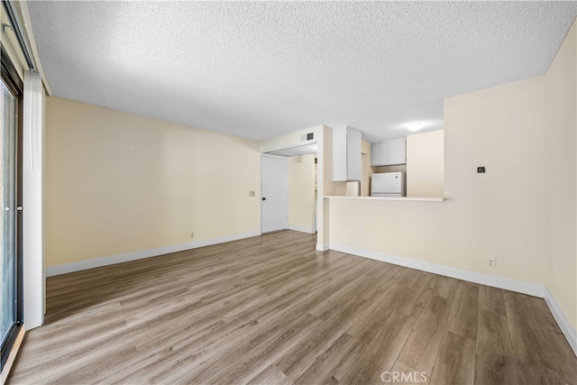 unfurnished living room with a textured ceiling and light wood-type flooring