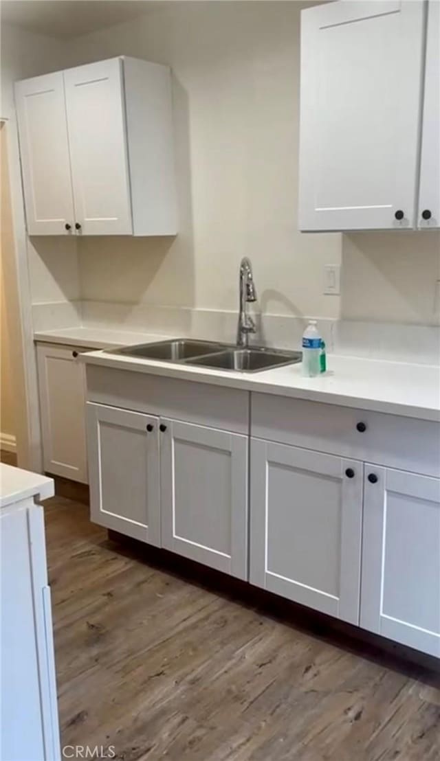 kitchen featuring white cabinetry, hardwood / wood-style floors, and sink