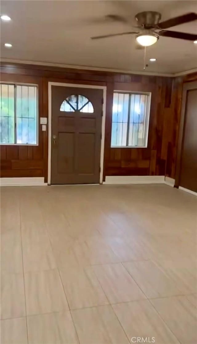 foyer with ceiling fan and wood walls