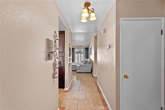 corridor with light tile patterned floors and an inviting chandelier