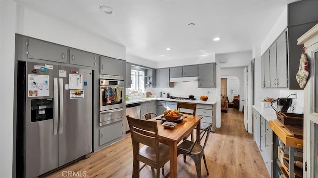 kitchen with appliances with stainless steel finishes, sink, gray cabinets, and light hardwood / wood-style floors