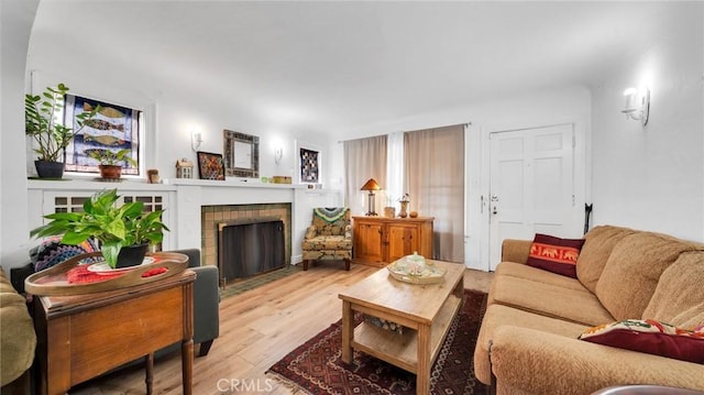 living room with a brick fireplace and light hardwood / wood-style flooring