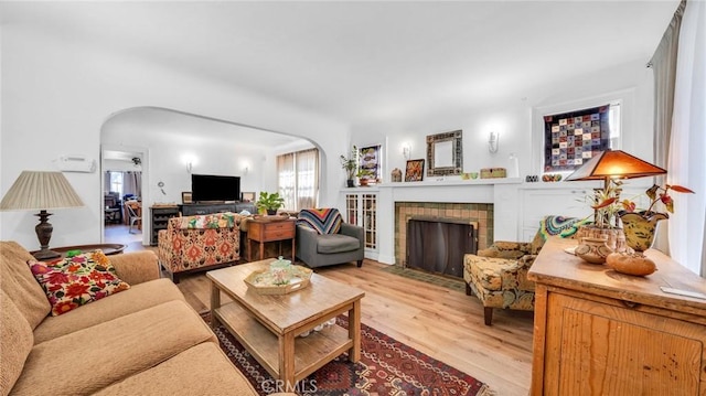 living room featuring a brick fireplace and light wood-type flooring