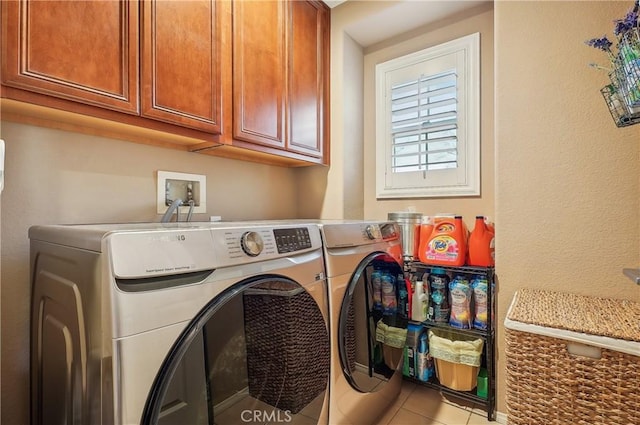 laundry room with cabinets, light tile patterned flooring, and washing machine and clothes dryer