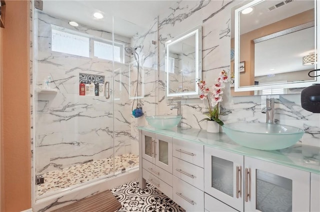 bathroom with vanity, backsplash, a shower with door, and tile walls