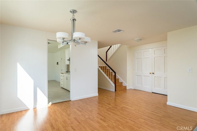 spare room with light hardwood / wood-style flooring and a notable chandelier