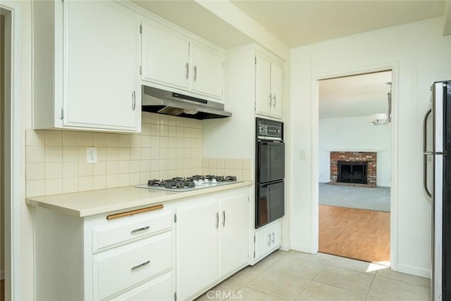 kitchen featuring stainless steel fridge, white gas cooktop, white cabinetry, and light tile patterned floors