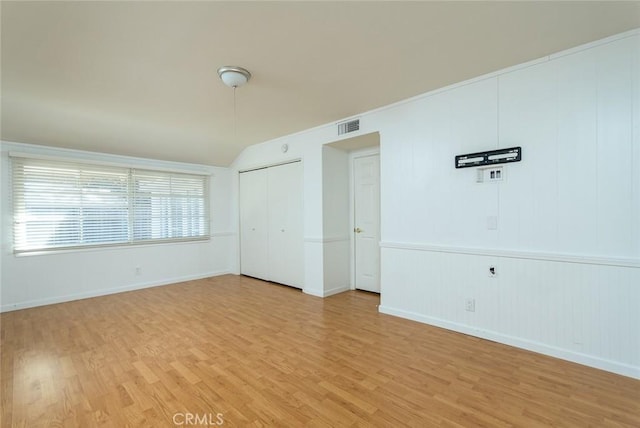 spare room featuring light wood-type flooring and lofted ceiling