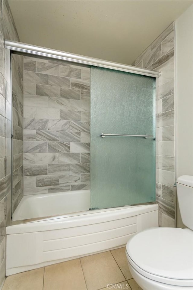 bathroom with tile patterned floors, shower / bath combination with glass door, and toilet