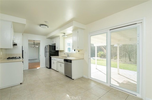 kitchen featuring white cabinets, appliances with stainless steel finishes, tasteful backsplash, plenty of natural light, and light tile patterned floors