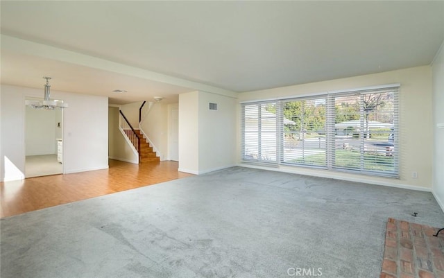 unfurnished room with an inviting chandelier and light colored carpet