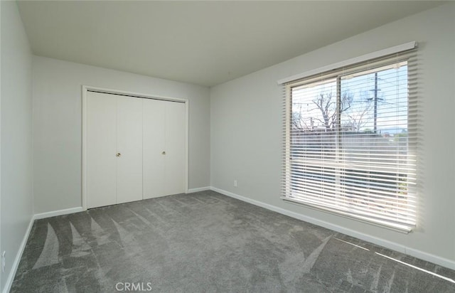 unfurnished bedroom featuring dark colored carpet and a closet