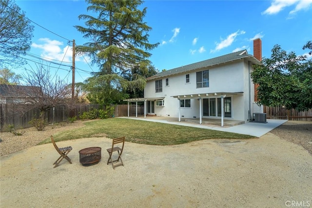 rear view of property with an outdoor fire pit, a lawn, central AC, and a patio area