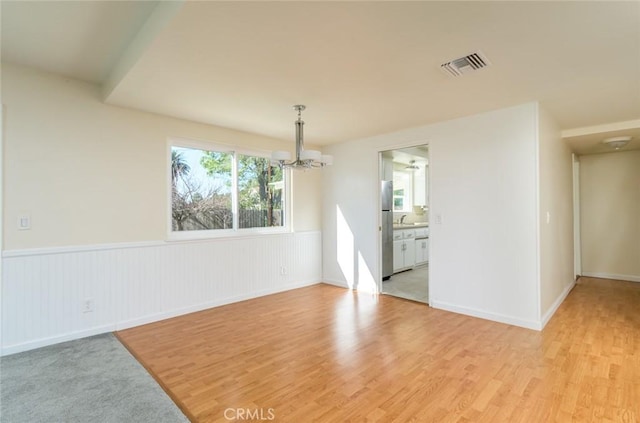 unfurnished room with an inviting chandelier and light wood-type flooring