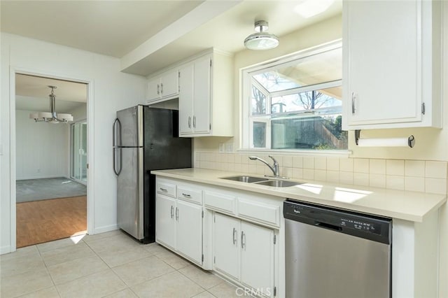 kitchen with white cabinets, stainless steel appliances, an inviting chandelier, sink, and light tile patterned floors