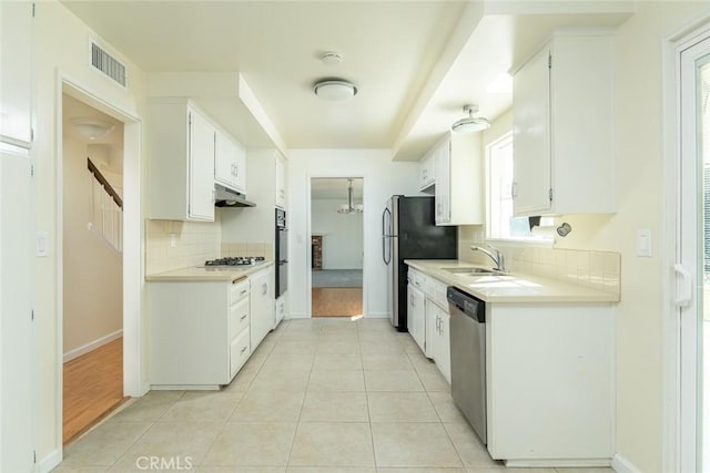 kitchen featuring appliances with stainless steel finishes, white cabinetry, sink, backsplash, and light tile patterned floors