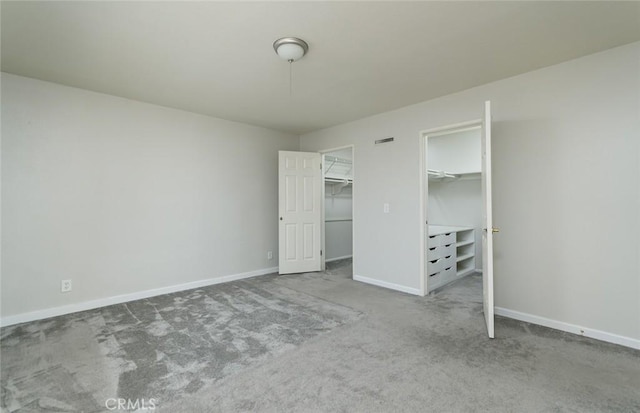 unfurnished bedroom with a closet, a spacious closet, and carpet floors