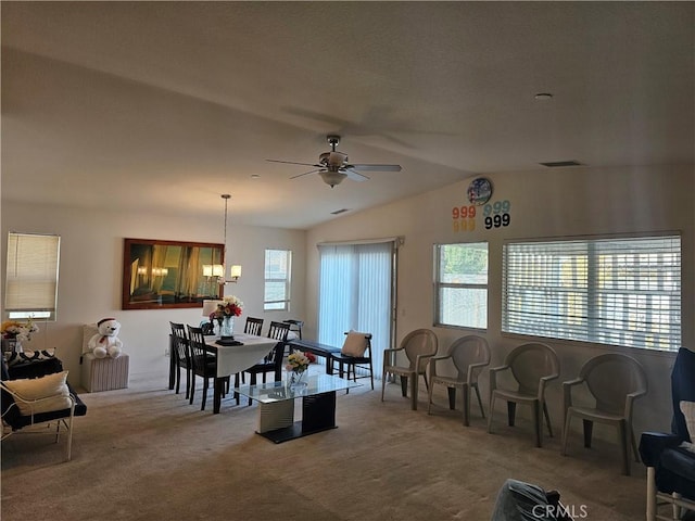 carpeted dining space featuring a healthy amount of sunlight, vaulted ceiling, and ceiling fan with notable chandelier