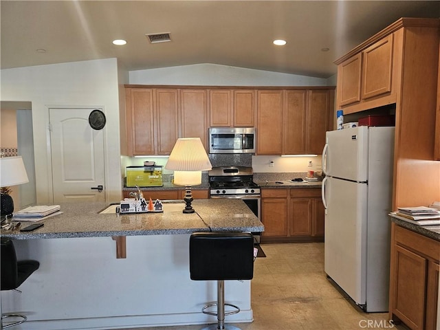 kitchen with a kitchen breakfast bar, appliances with stainless steel finishes, lofted ceiling, and sink