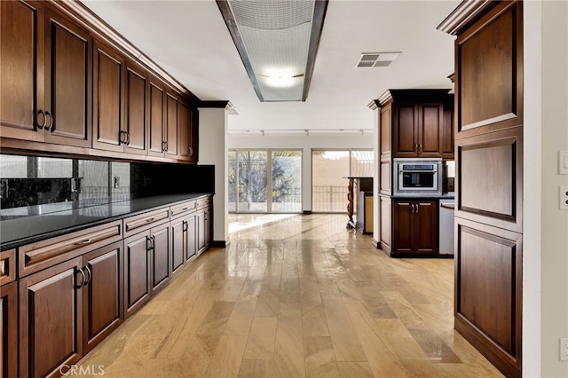 kitchen featuring backsplash, dark brown cabinets, and light hardwood / wood-style flooring