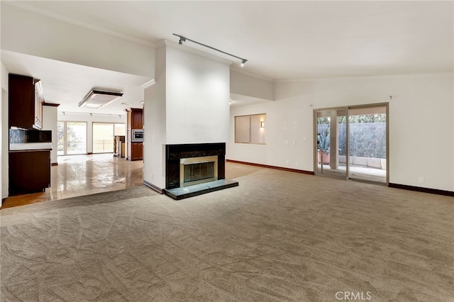 unfurnished living room featuring lofted ceiling, a fireplace, light colored carpet, and rail lighting