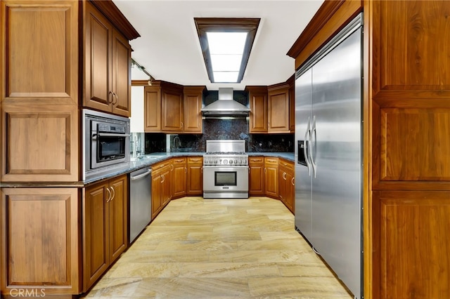 kitchen with tasteful backsplash, wall chimney exhaust hood, and premium appliances