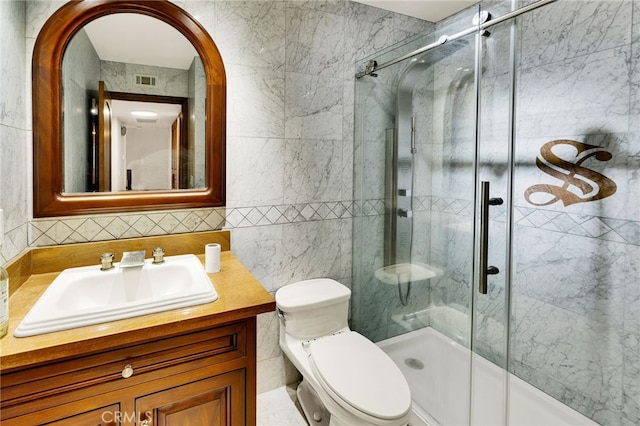 bathroom with tile walls, vanity, toilet, and an enclosed shower