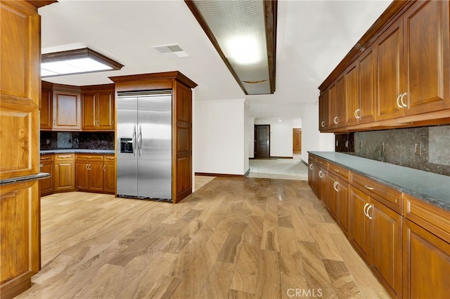 kitchen featuring tasteful backsplash, dark stone counters, and built in fridge