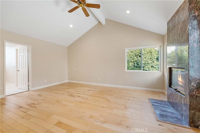 unfurnished living room featuring ceiling fan, light hardwood / wood-style flooring, beam ceiling, and a tiled fireplace