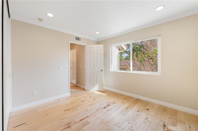 spare room featuring light wood-type flooring and crown molding