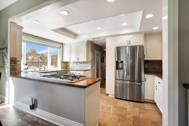 kitchen featuring white cabinetry, appliances with stainless steel finishes, a raised ceiling, and kitchen peninsula