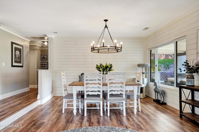 dining space featuring dark hardwood / wood-style floors, crown molding, and a chandelier