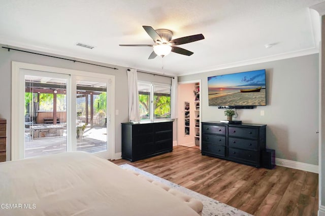 bedroom with ceiling fan, access to exterior, multiple windows, and hardwood / wood-style flooring