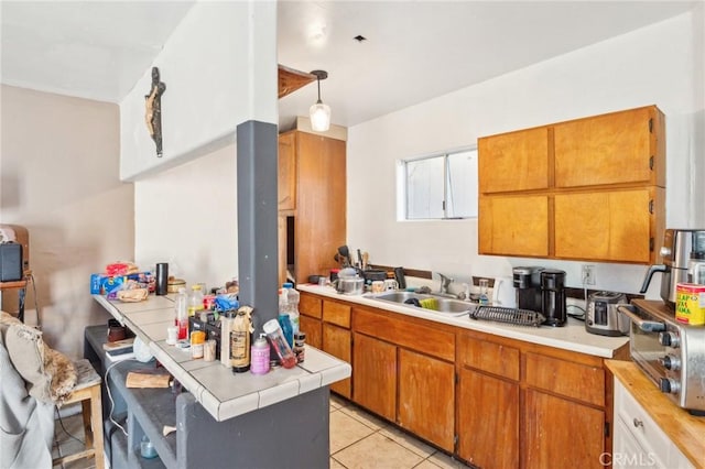 kitchen with sink, pendant lighting, light tile patterned floors, and tile countertops