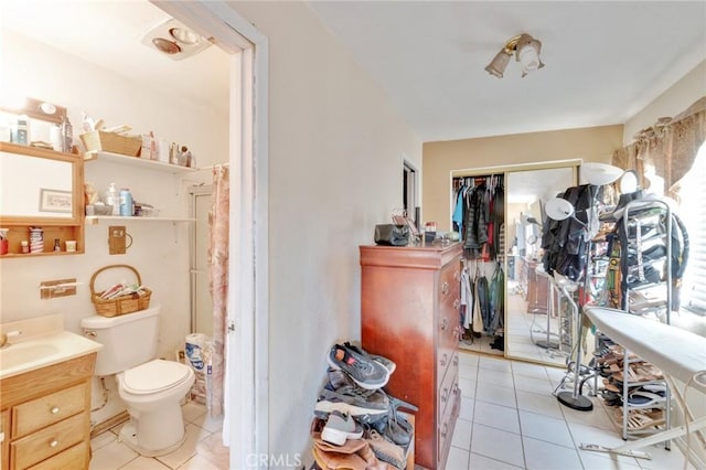 bathroom with toilet, vanity, and tile patterned flooring