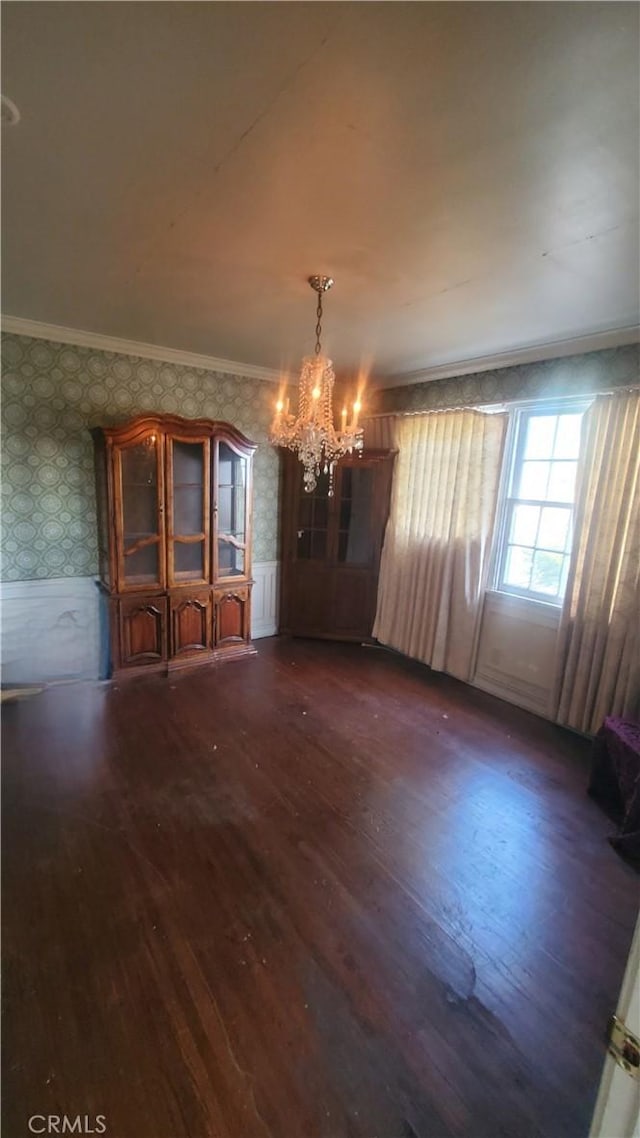 unfurnished dining area with a chandelier, ornamental molding, and dark hardwood / wood-style floors