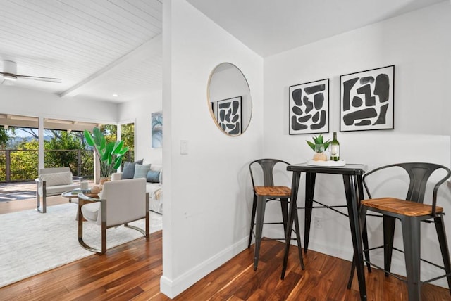 dining room featuring ceiling fan, dark hardwood / wood-style flooring, and beamed ceiling