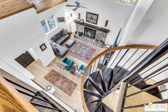 living room featuring wood-type flooring, plenty of natural light, a stone fireplace, and a towering ceiling