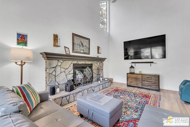 living room with light wood-type flooring and a stone fireplace