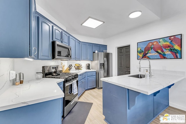 kitchen with kitchen peninsula, sink, blue cabinetry, and stainless steel appliances