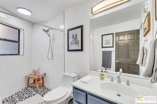 bathroom with toilet, vanity, and a tile shower